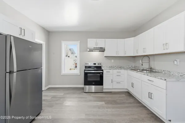a kitchen with granite countertop white cabinets and refrigerator