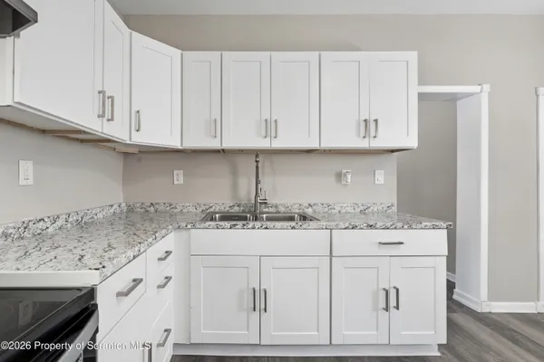a kitchen with granite countertop white cabinets and a sink