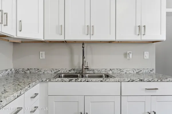 a kitchen with granite countertop white cabinets and a sink
