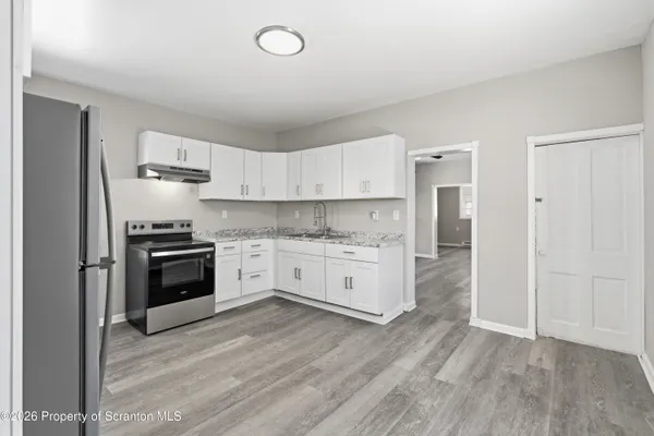a kitchen with granite countertop a refrigerator and a stove top oven