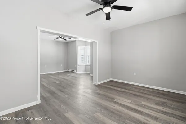 an empty room with a ceiling fan and wooden floor