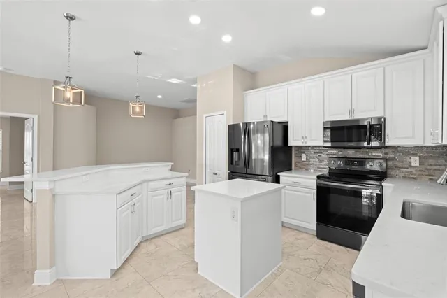 a kitchen that has a lot of white cabinets and stainless steel appliances