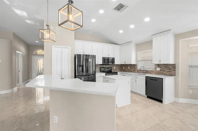 a kitchen with stainless steel appliances granite countertop a refrigerator a sink dishwasher a stove and white cabinets with wooden floor