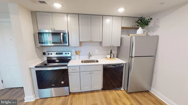 a kitchen with a sink a refrigerator and a stove top oven