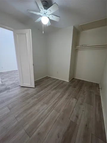 an empty room with wooden floor and ceiling fan