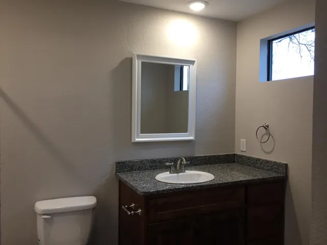 a bathroom with a granite countertop sink and a toilet