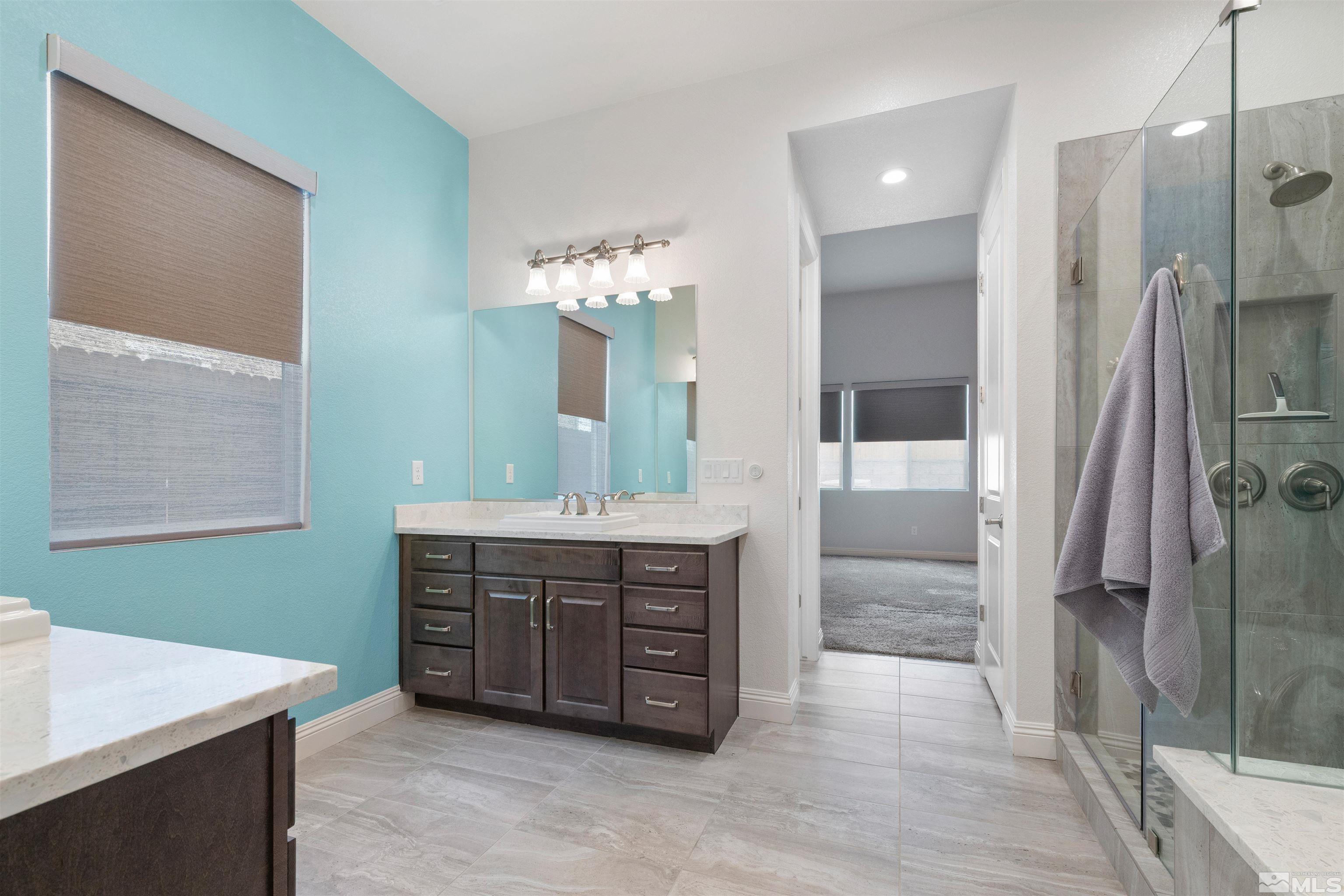 9404 Flying Horse Road Reno, NV 89521 - Photo 23 of 40 a spacious bathroom with a granite countertop sink a mirror and a shower