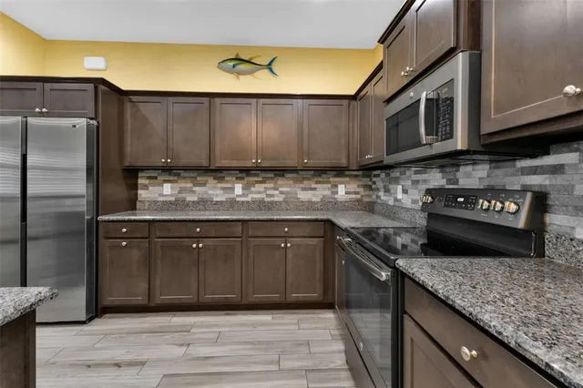a kitchen with stainless steel appliances granite countertop a stove a sink and a microwave