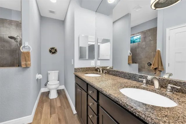 a bathroom with a granite countertop double vanity sink and a mirror