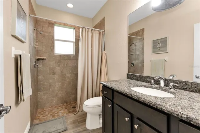 a bathroom with a granite countertop sink toilet and shower