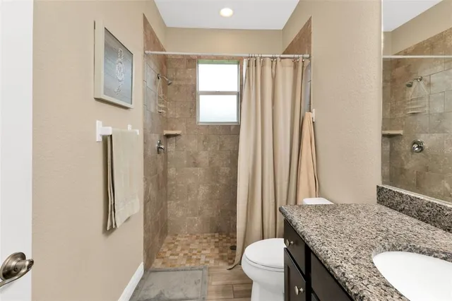 a bathroom with a granite countertop sink toilet and shower
