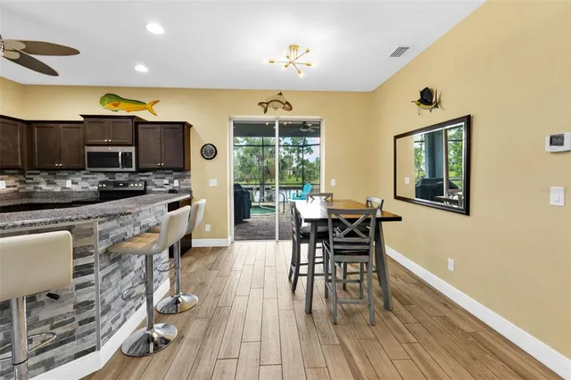 a kitchen with stainless steel appliances granite countertop a stove top oven a sink a dining table and chairs with wooden floor