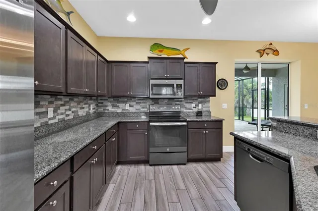 a kitchen with stainless steel appliances granite countertop wooden cabinets a stove top oven a sink and dishwasher