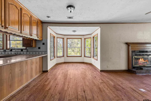 a kitchen with stainless steel appliances granite countertop a refrigerator a sink dishwasher and wooden cabinets with wooden floor