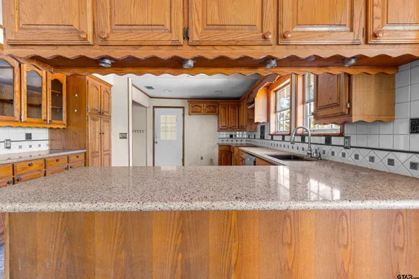 a large kitchen with granite countertop a sink and cabinets