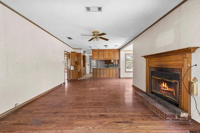 a view of a living room a fireplace with wooden floor and a ceiling fan