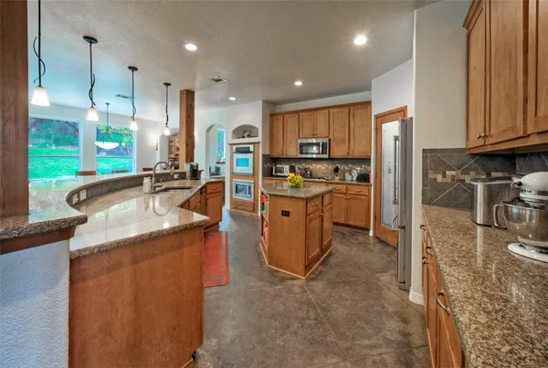a kitchen with stainless steel appliances kitchen island granite countertop a sink stove and cabinets