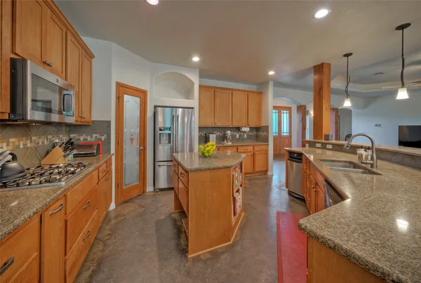 a kitchen with stainless steel appliances granite countertop a stove a sink a refrigerator and a wooden cabinets