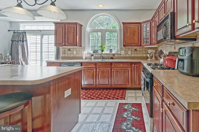 a kitchen with stainless steel appliances granite countertop a stove a sink dishwasher and cabinets with wooden floor