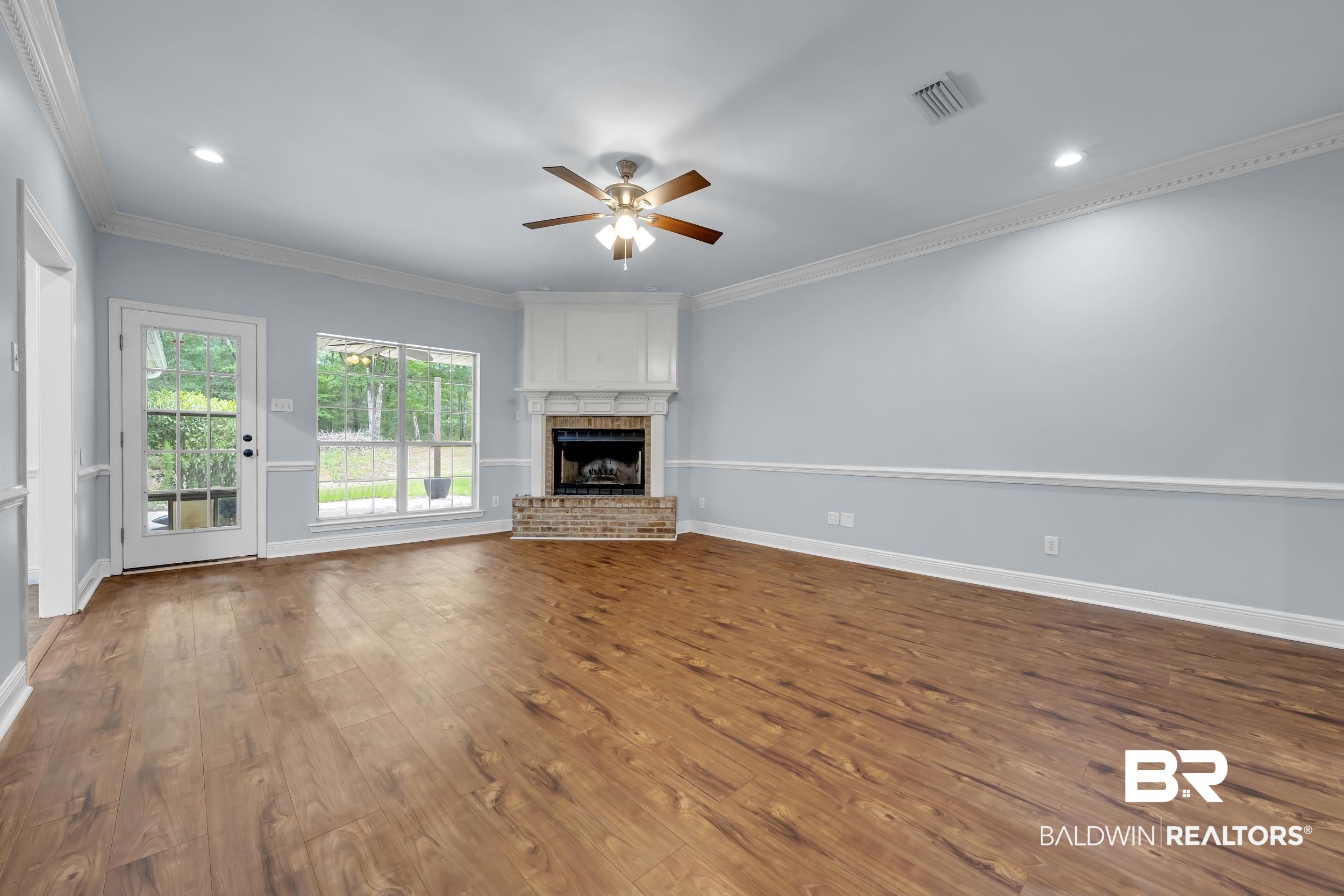 14960 Howells Ferry Road Wilmer, AL 36587 - Photo 8 of 22 Spacious interior with wood-finish flooring, a corner fireplace with a brick hearth, and crisp white trim
