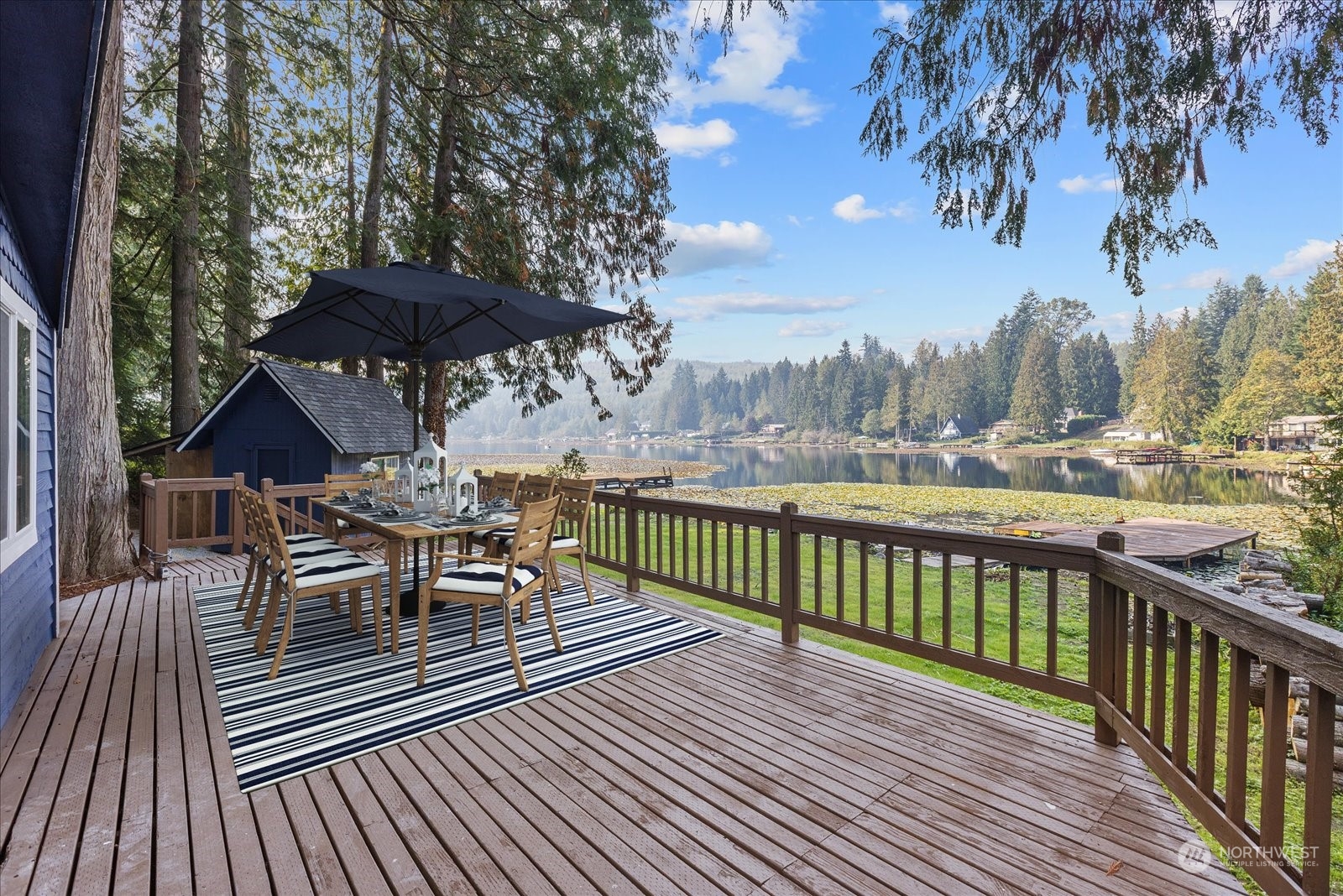 1024 South Lake Roesiger Road Snohomish, WA 98290 - Photo 23 of 35 a view of a roof deck with table and chairs under an umbrella with wooden floor and fence