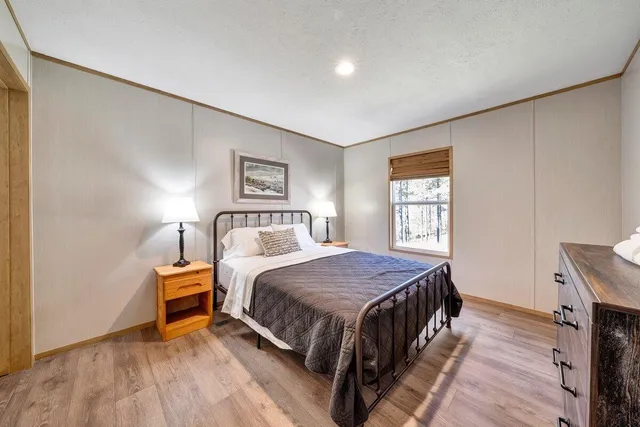 a bedroom with a bed and a dresser next to a window