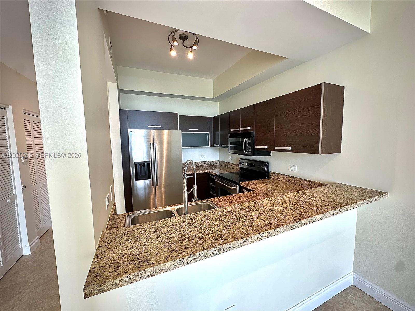 2525 Southwest 3rd Avenue, Unit 705 Miami, FL 33129 - Photo 5 of 26 a kitchen with stainless steel appliances granite countertop a sink refrigerator and microwave