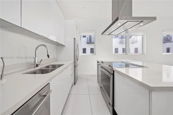 a kitchen with stainless steel appliances granite countertop a sink a stove top oven and cabinets