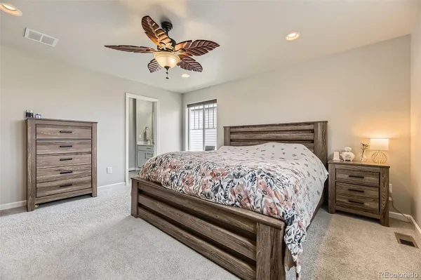 a bedroom with a bed a dresser and a chandelier
