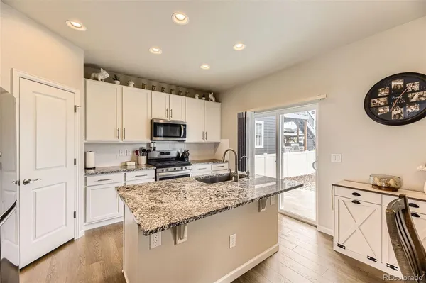 a kitchen with a refrigerator a stove top oven a sink and dishwasher with wooden floor