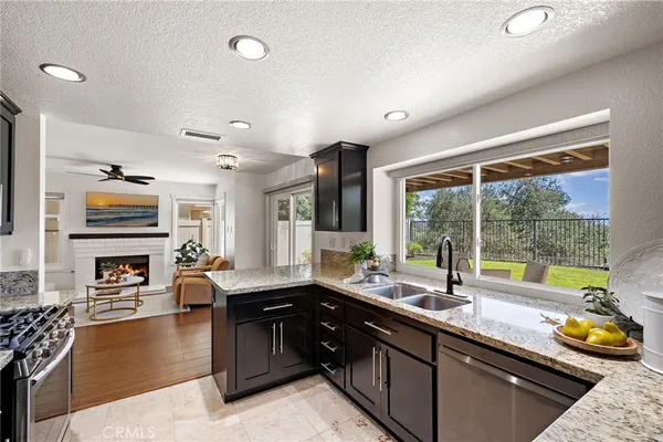a kitchen with granite countertop kitchen island stainless steel appliances a sink stove refrigerator and cabinets