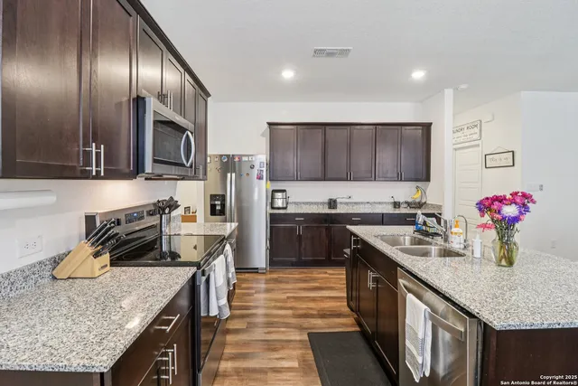 a kitchen with kitchen island granite countertop a stove sink and cabinets