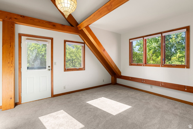 435 Canyon Road Millville, UT 84326 - Photo 28 of 113 Exposed wood beams and trim accents a room featuring multiple windows, a paneled door, and neutral carpeting