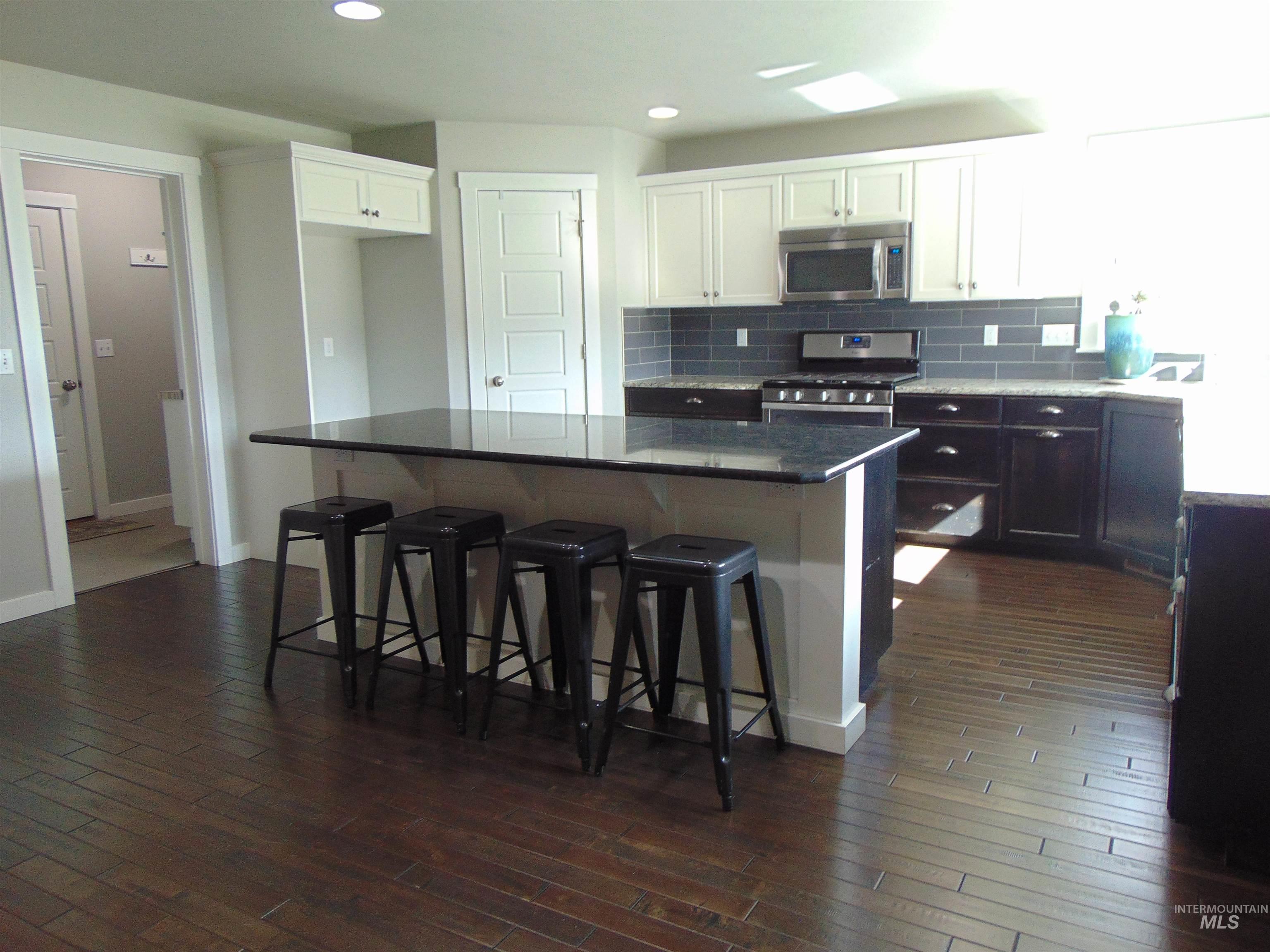 983 South Street Vale, OR 97918 - Photo 11 of 36 Two tone kitchen with a breakfast bar, dark stone countertops, stainless steel appliances, a kitchen island, and dual tone cabinetry