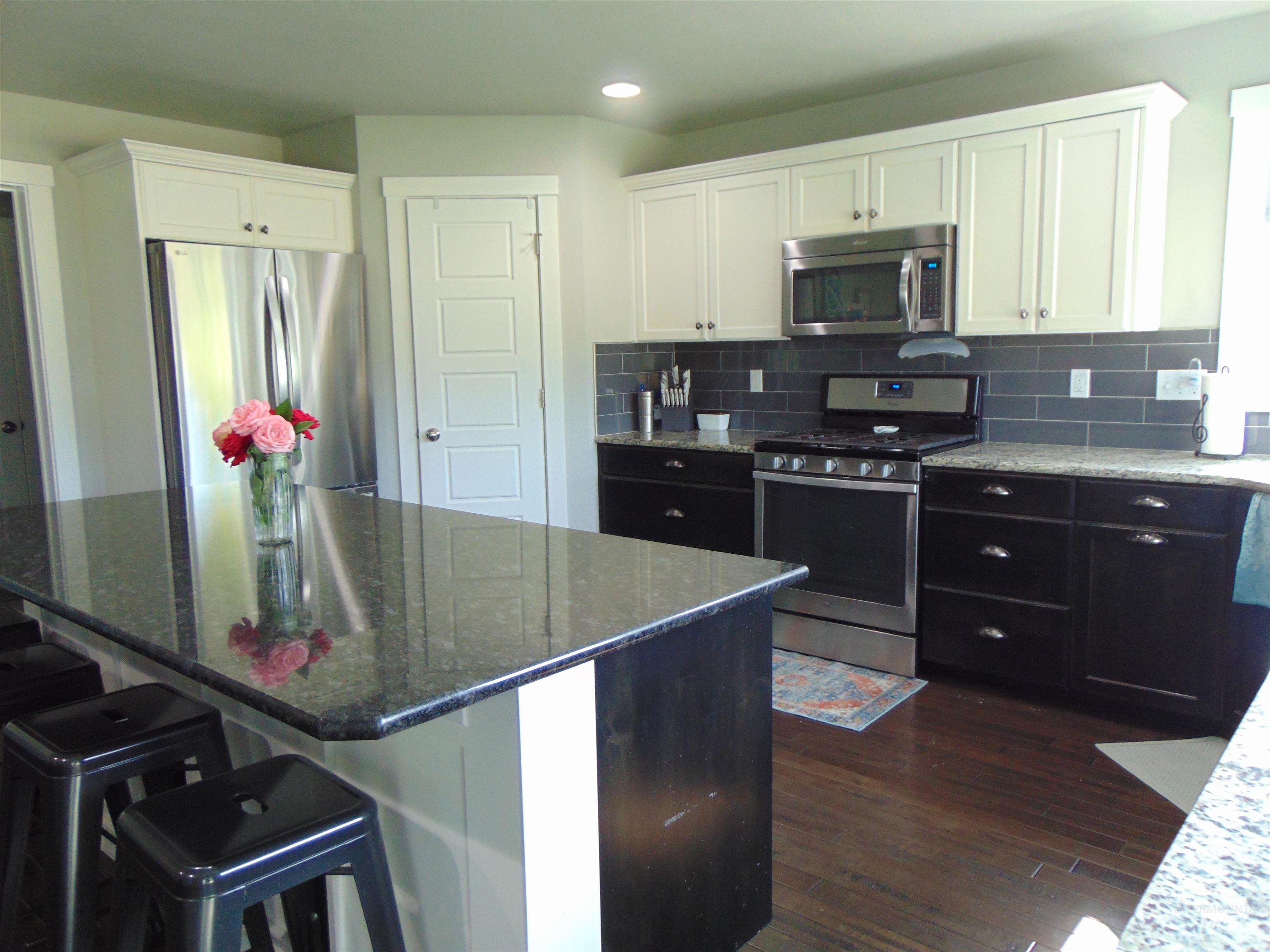 983 South Street Vale, OR 97918 - Photo 13 of 36 Kitchen featuring appliances with stainless steel finishes, white cabinetry, dark wood-type flooring, dark stone counters, and recessed lighting