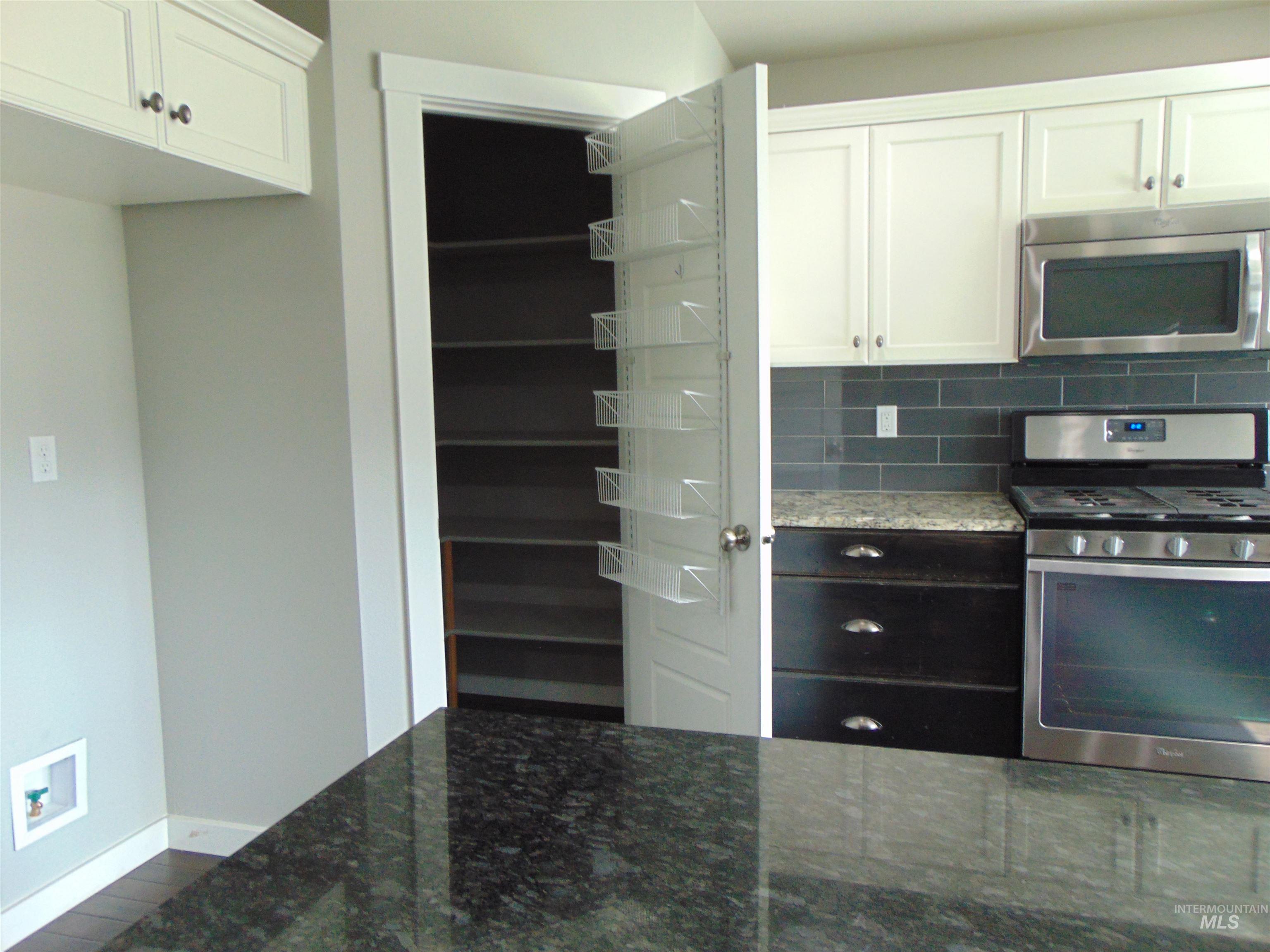 983 South Street Vale, OR 97918 - Photo 14 of 36 Dual tone kitchen featuring dark stone countertops, stainless steel appliances, tasteful backsplash, and two tone color scheme