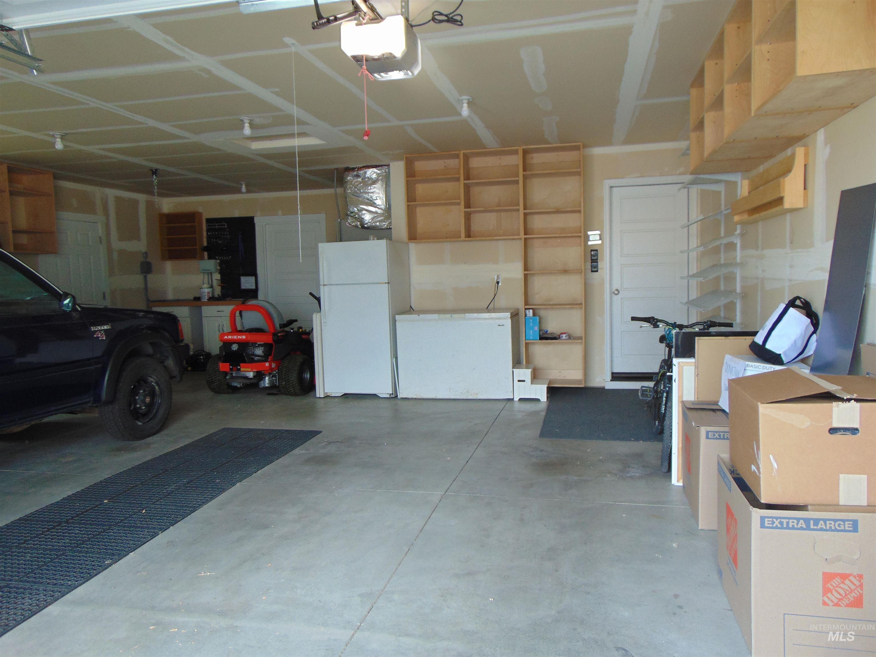 983 South Street Vale, OR 97918 - Photo 31 of 36 Garage with white fridge, freestanding refrigerator, and a garage door opener