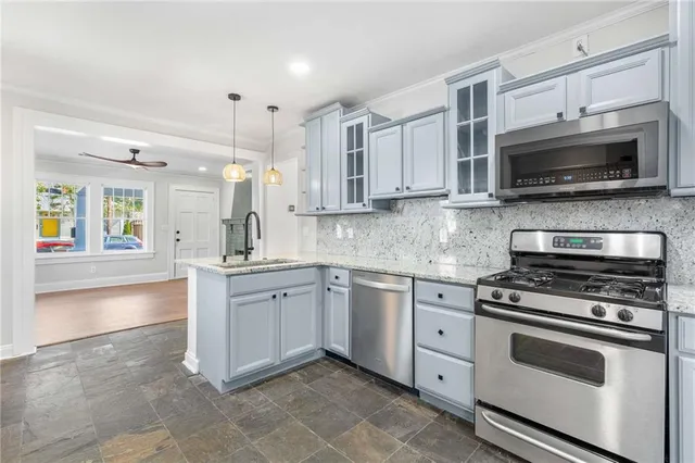 a kitchen with stainless steel appliances granite countertop grey cabinets a stove a sink and a microwave