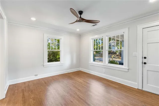 a view of an empty room with wooden floor and a window
