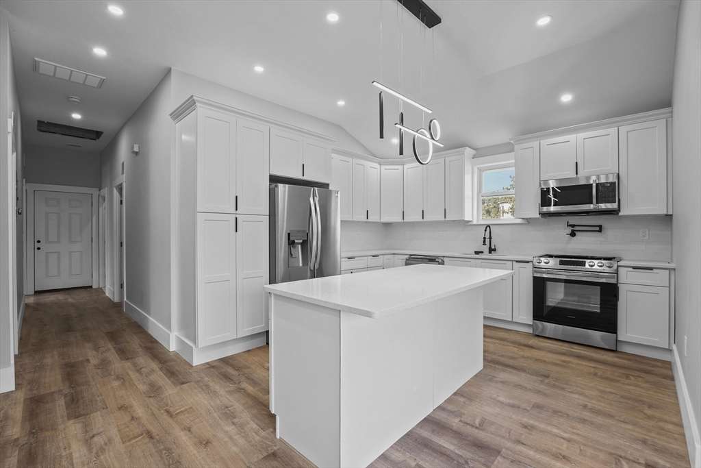 19-21 Standard Street, Unit 3 Boston, MA 02126 - Photo 2 of 23 a kitchen with kitchen island a sink stainless steel appliances and cabinets
