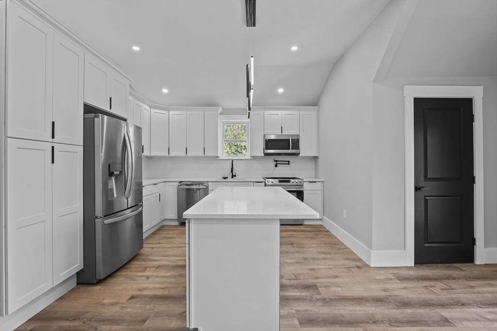 19-21 Standard Street, Unit 3 Boston, MA 02126 - Photo 9 of 23 a kitchen with kitchen island white cabinets and stainless steel appliances