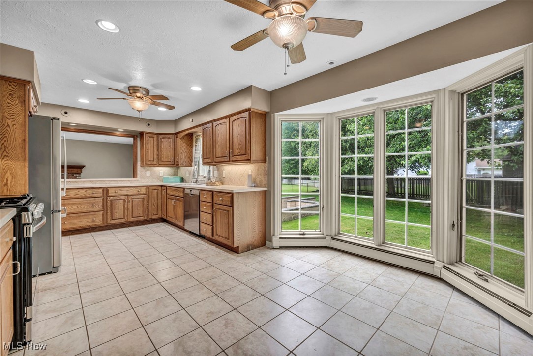 38814 Johnnycake Ridge Road Willoughby, OH 44094 - Photo 15 of 48 Kitchen with stainless steel appliances, a ceiling fan, light countertops, light tile patterned flooring, and brown cabinets