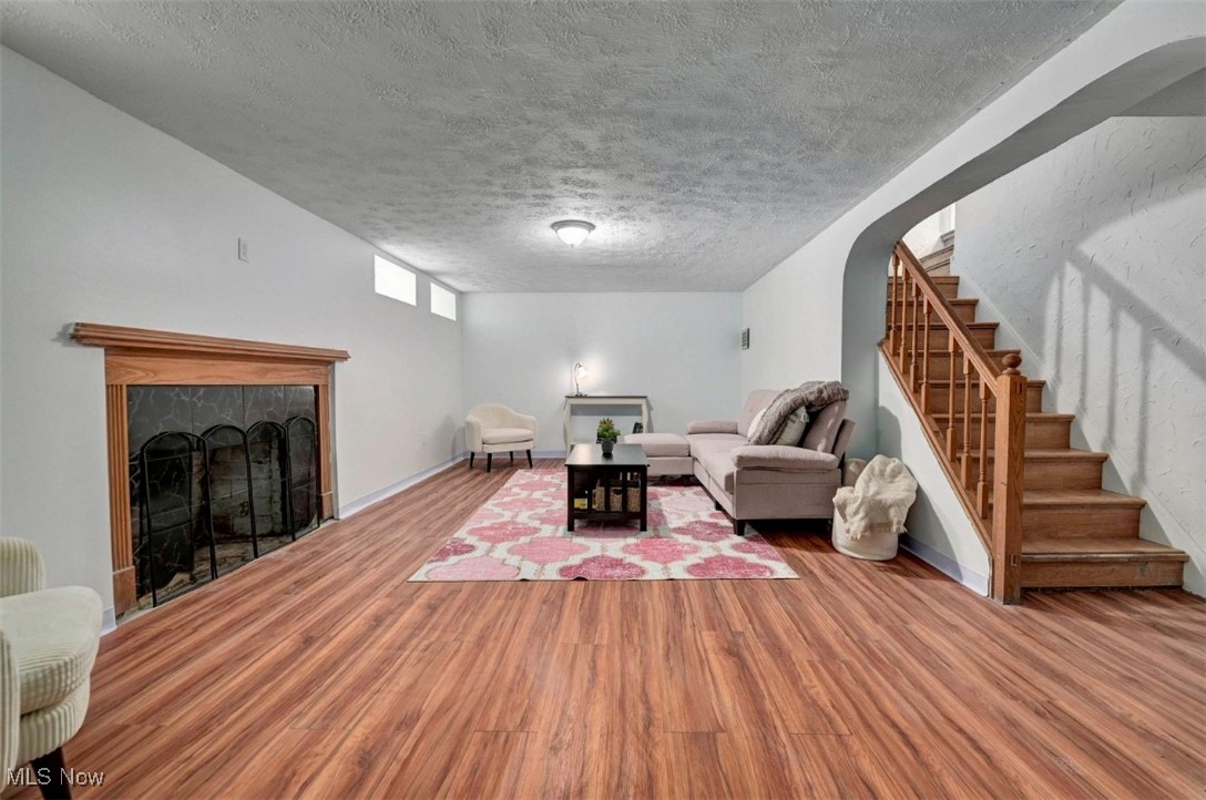 3693 Warren Road Cleveland, OH 44111 - Photo 25 of 37 Rec room area with wood finished floors, a textured ceiling, a tiled fireplace, stairway, and arched walkways