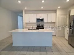 a kitchen with stainless steel appliances a refrigerator a sink a stove a microwave and cabinets