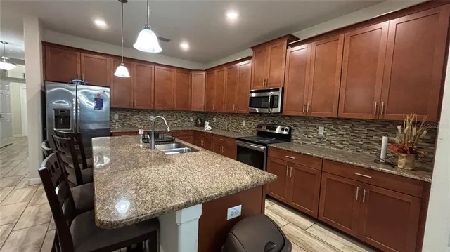 a kitchen with granite countertop kitchen island stainless steel appliances a sink a stove cabinets counter space and a window
