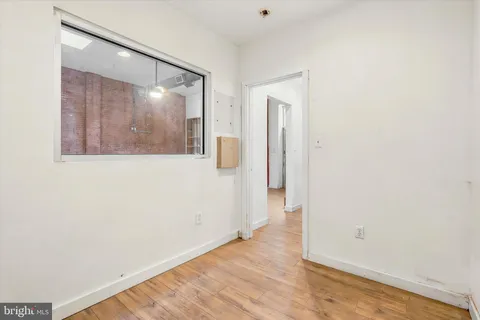 an empty room with wooden floor and a bathroom