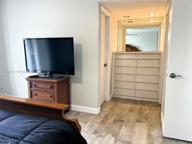 a living room with a flat screen tv on dresser and a window
