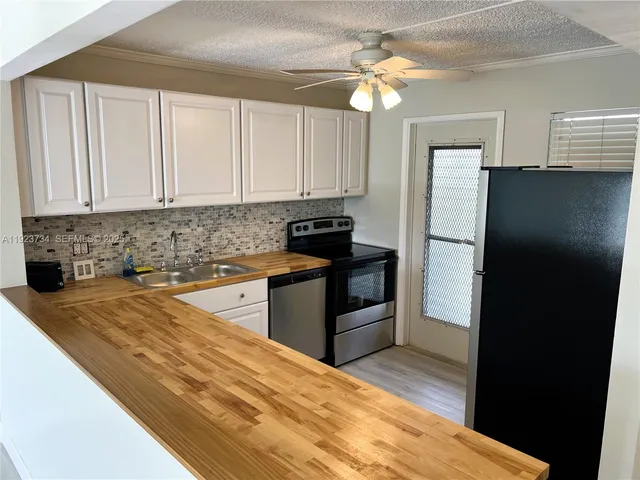 a kitchen with granite countertop a refrigerator stove and sink