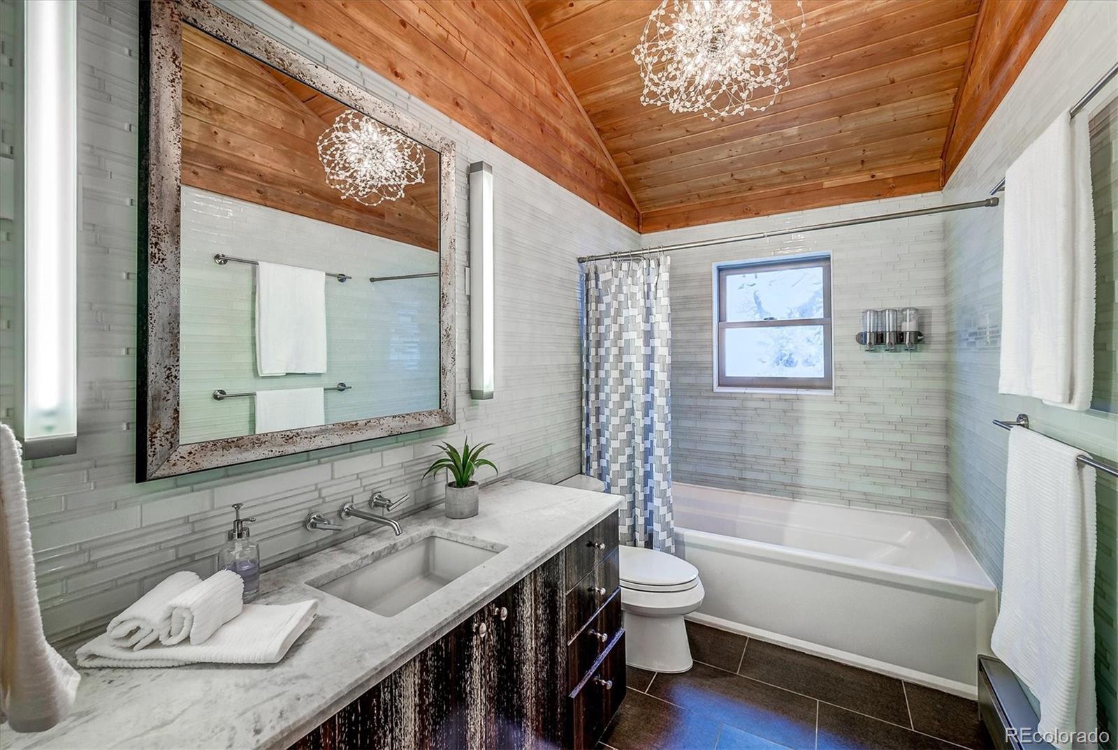 9055 Eagle Cliff Road Conifer, CO 80433 - Photo 22 of 39 a bathroom with a granite countertop sink a toilet a mirror and shower