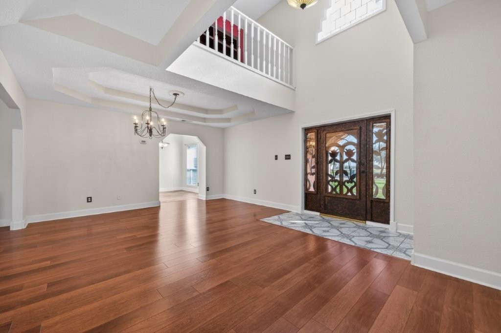 6610 Sprigg Street Fulshear, TX 77441 - Photo 10 of 49 a view of a hallway with wooden floor and a chandelier